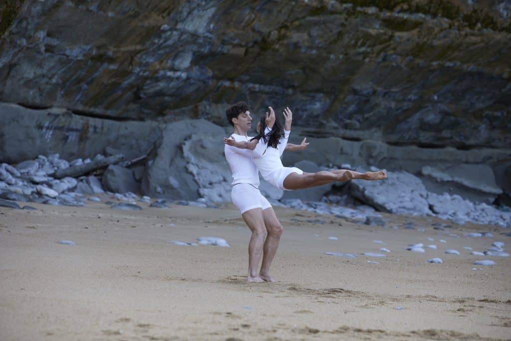 Zwei Tanzende bei einer Hebefigur an einem felsigen Strand in weißer Feinripp-Wäsche von SCHIESSER